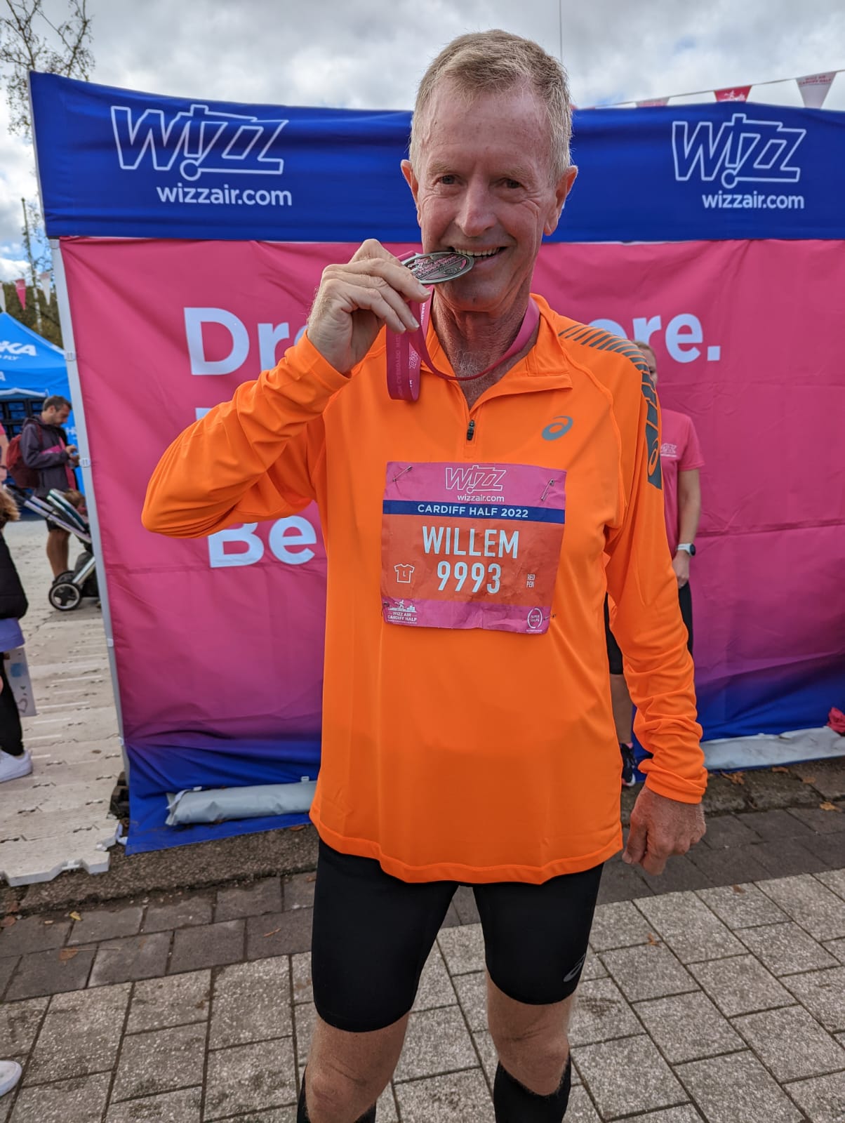 Wil, has just run the Cardiff Half Marathon. He's wearing his medal and biting down on it.