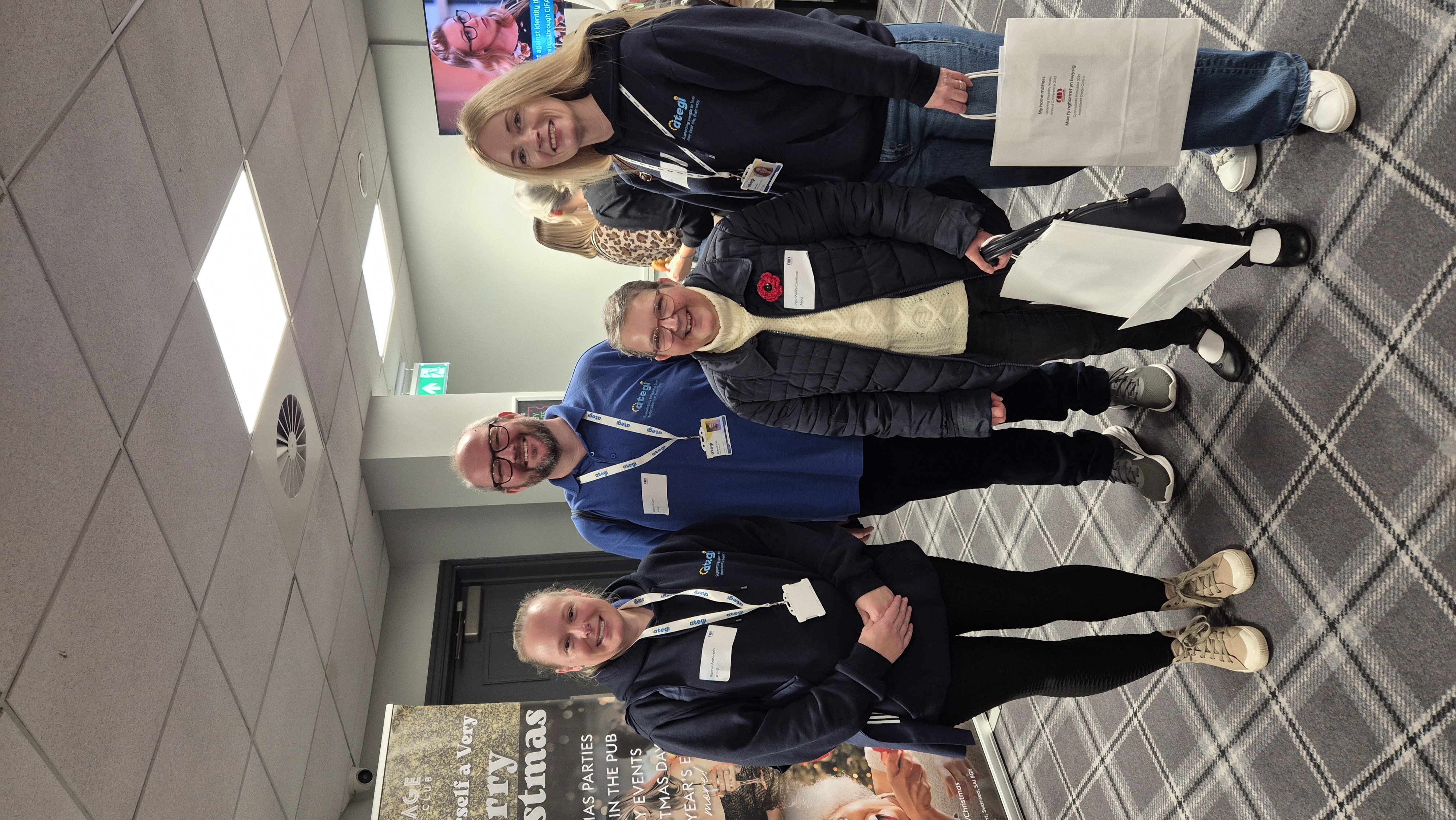 3 women & 1 man standing at a conference smiling