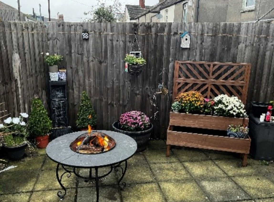 A small patio garden with a fire pit and potted flowers