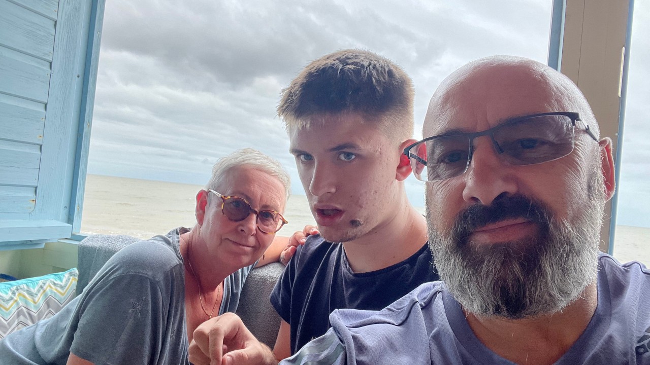 A man taking a selfie with a young man and a woman sat in front of a window