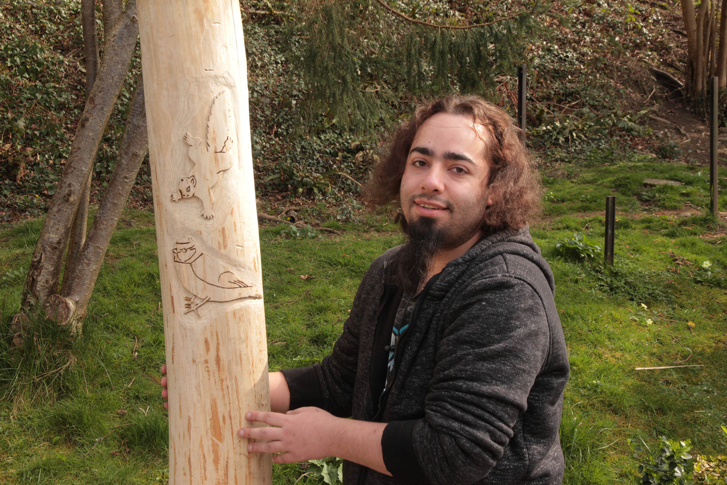 Kyeron holding a totem pole he carved