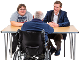 Three people talking around a table, one is in a wheelchair. 