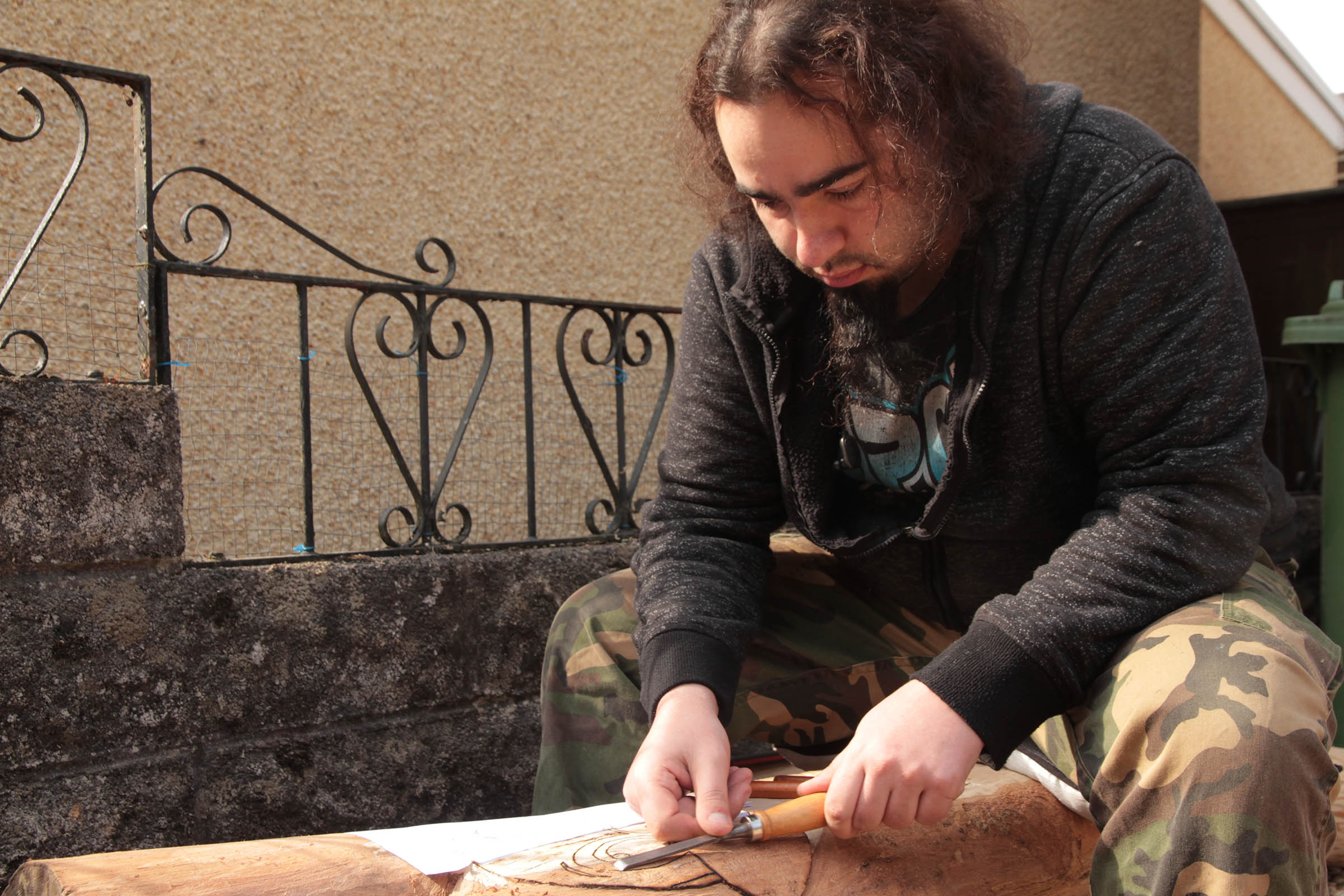 Kyeron outside his house, working on a woodwork project