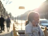 A woman outside, on the phone smiling