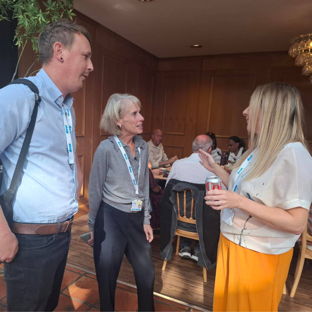 Three Ategi colleagues pictured standing and deep in conversation with each other