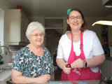 Wendy cooking with her Shared Lives carer, Grazelda. Both women are smiling at the camera.