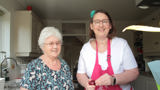 Wendy cooking with her Shared Lives carer, Grazelda. Both women are smiling at the camera.
