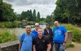 Support circles volunteers stnading and smiling for camera with a lake behind them, 