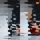 Someone with a open lap top holding a credit card. 