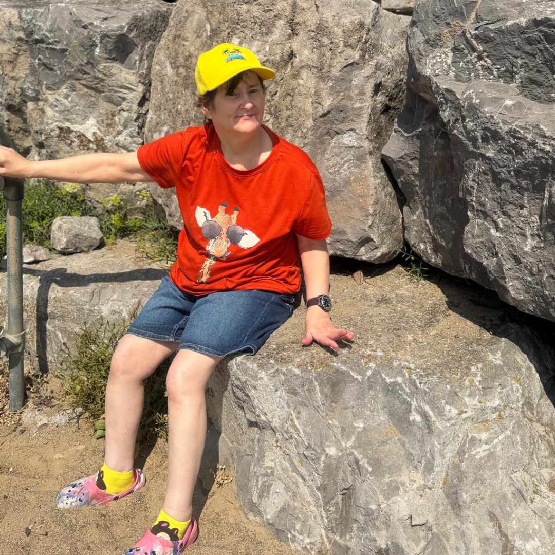 An image picturing Liz sitting on a rock on the beach.