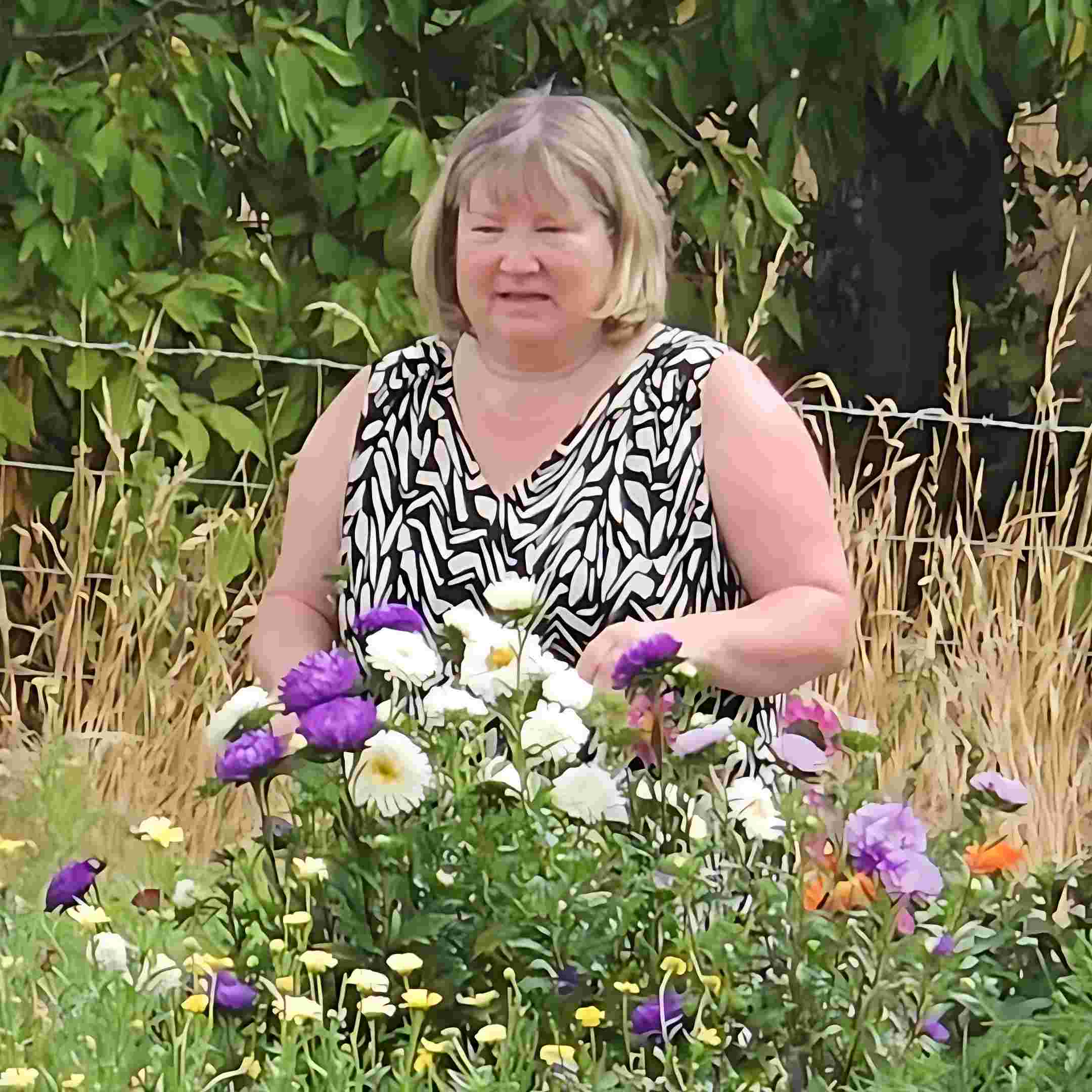 A picture of volunteer Nikki amongst the flowers at Bloomin Well CIC