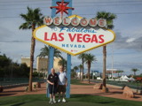 Two older men stood in front of a really big Welcome to Las Vegas sign. 
