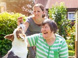 Two women playing with a dog. 