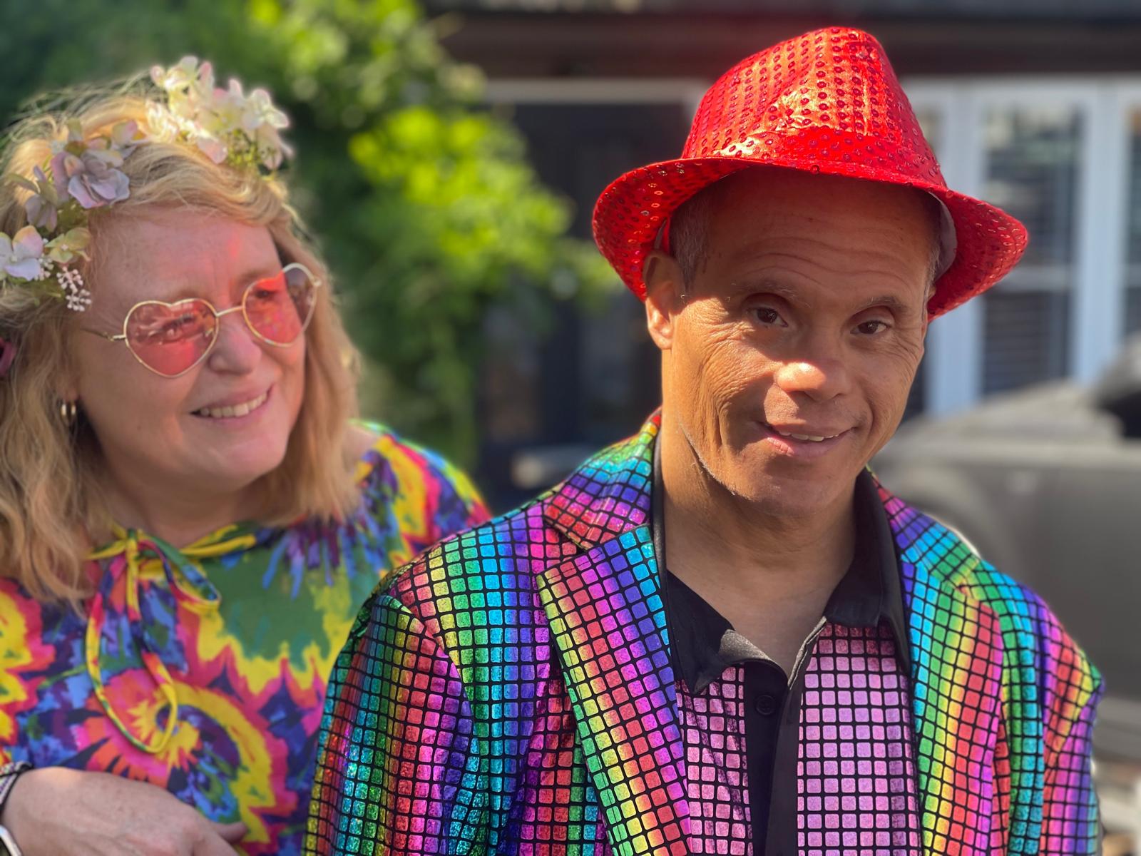 Kam with one of his Shared Lives carers, they're dressed in rainbow colours.