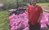Danny stood in front of lots of full pink bink bags from litter picking. 