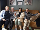 Two women, two men and one large dog sat on a sofa together smiling