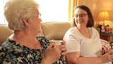 Wendy having a cup of tea with her Shared Lives carer, Grazelda. Both women are smiling. 