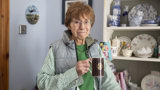 An older woman at home smiling with a cup of tea