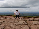 A man in a white t shirt on top of Pen Y Fan. 