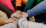 Lots of hands on top of each other in a circle.