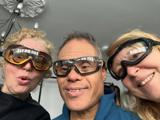 Three adults smiling together whilst wearing goggles